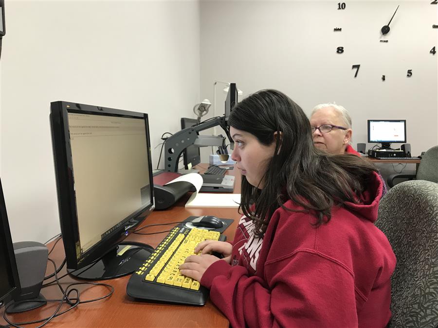A consumer who is blind working on a computer.